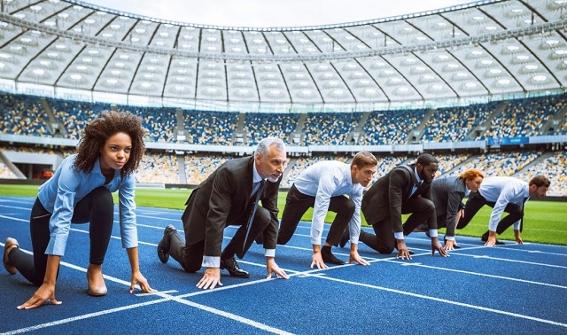Métiers du sport business : professionnels prêts à démarrer sur une piste d'athlétisme, symbolisant la compétition et les opportunités de carrière.

